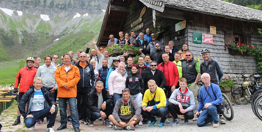 DMC in Alps – A large group of travelers gathered in front of a rustic mountain hut