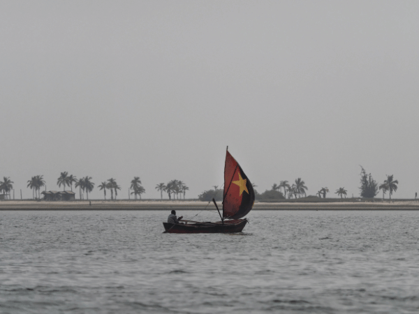 Traditional Angolan fishing boat with a red and yellow star sail, representing local culture for DMC Angola experiences