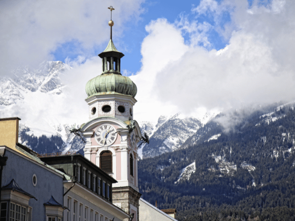 Historic church tower in Innsbruck with snowy Alps backdrop – DMC in Austria travel experience