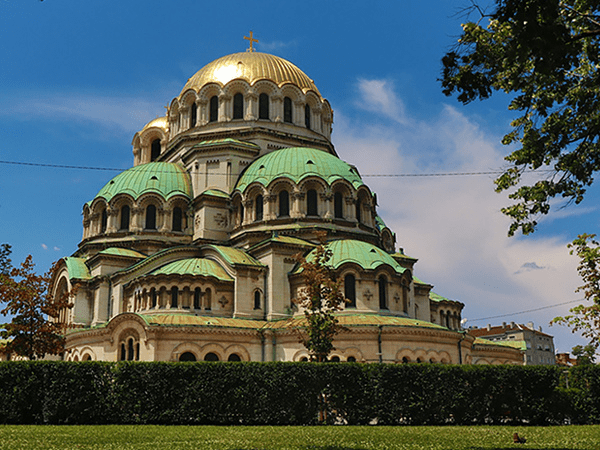The iconic Alexander Nevsky Cathedral in Sofia, Bulgaria, highlighted by a DMC in Bulgaria, with its golden dome and green rooftops against a bright blue sky.