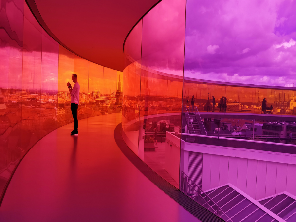 DMC in Denmark – A person in the colorful, panoramic walkway of ARoS Aarhus Art Museum, showcasing vibrant architecture and culture.