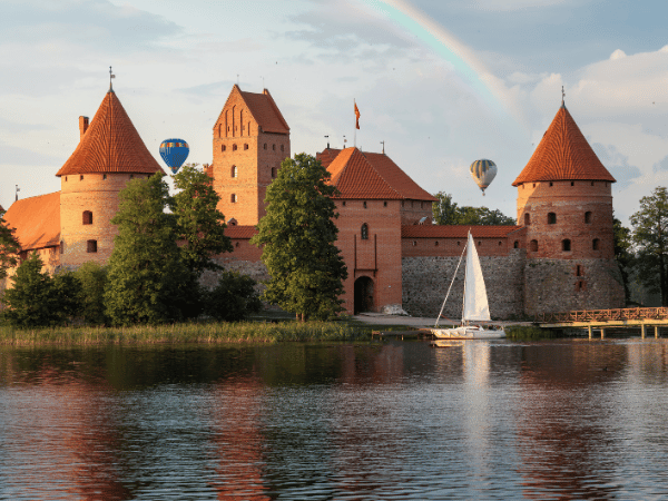 DMC in Lithuania – Trakai Castle with a rainbow over Lake Galvė, ideal for MICE and leisure tours.