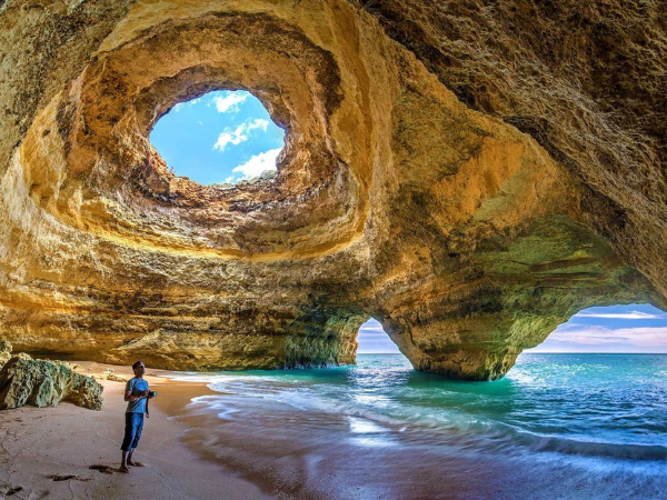 The stunning Benagil Cave in the Algarve, Portugal, a must-visit attraction with a DMC in Portugal, featuring sunlight streaming through a natural rock opening.