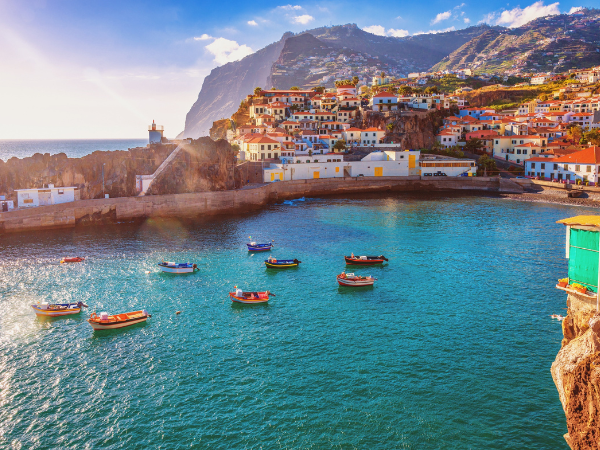 The picturesque harbor of Câmara de Lobos, Madeira, Portugal, with vibrant fishing boats and hillside houses, a hidden gem explored with a DMC in Portugal.