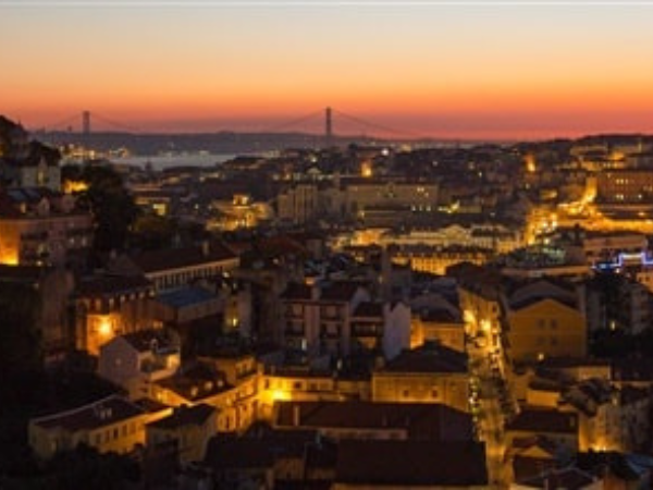  mesmerizing night view of Lisbon, Portugal, with city lights and the 25 de Abril Bridge, showcasing the charm of the capital with a DMC in Portugal.