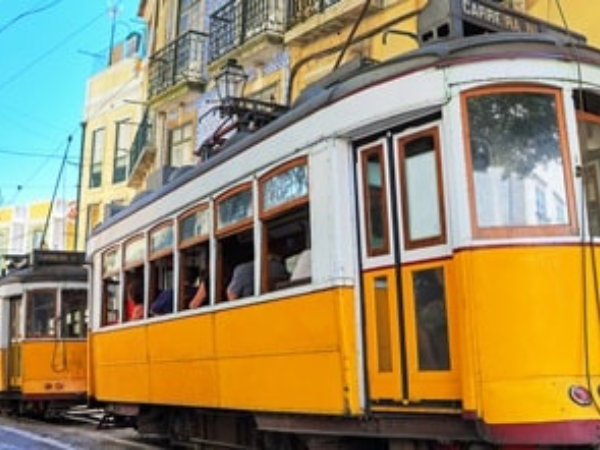 A classic yellow tram climbing Lisbon’s steep streets, passing historic buildings, a top experience arranged by a DMC in Portugal.