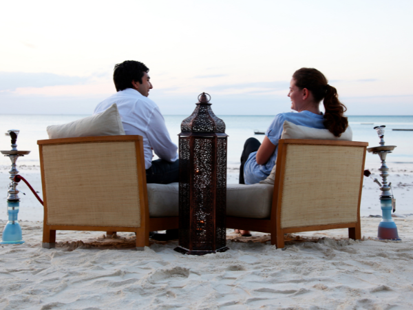 A couple in Zanzibar smoking shisha on a beach